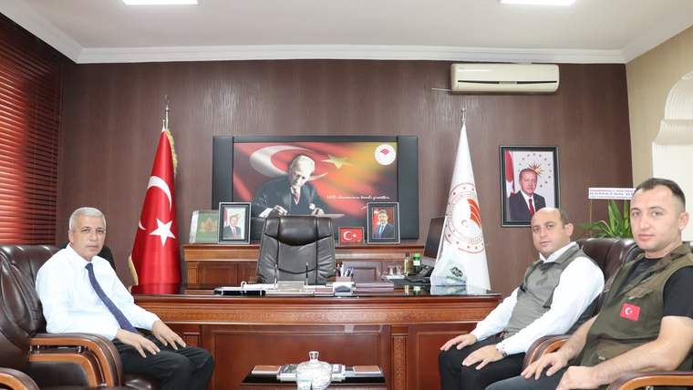 Sivas Tarım ve Orman Müdürlüğü'nde üç kişi, bir masanın etrafında oturuyor. Arka planda Türk bayrağı ve Atatürk'ün resmi var.