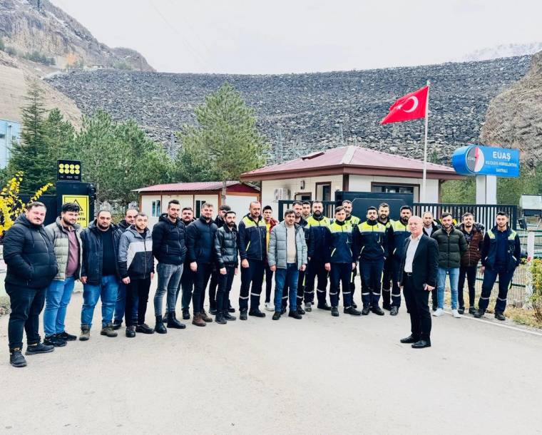 Türk bayrağı önünde, baraj duvarı ve küçük bir bina önünde duran kalabalık grup