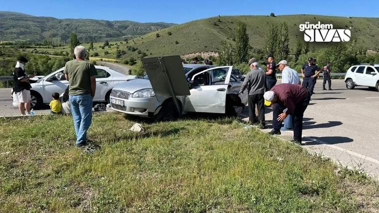 Yolda duran bir otomobilin yanında birkaç kişi toplanmış, bir başka otomobil ise yolun kenarında duruyor.