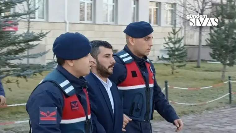 İki polis memuru, bir kişiyi kolundan tutarak yürütüyor.