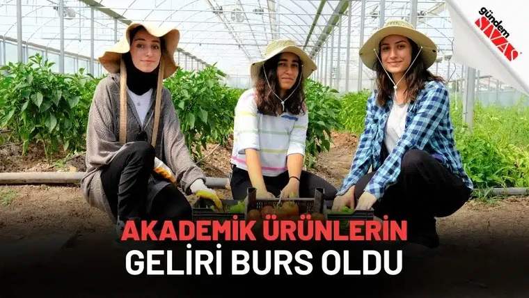 Serada çalışan üç genç kadın, sebze yetiştiriyor. Hepsi şapka takıyor ve gülümseyerek poz veriyor.