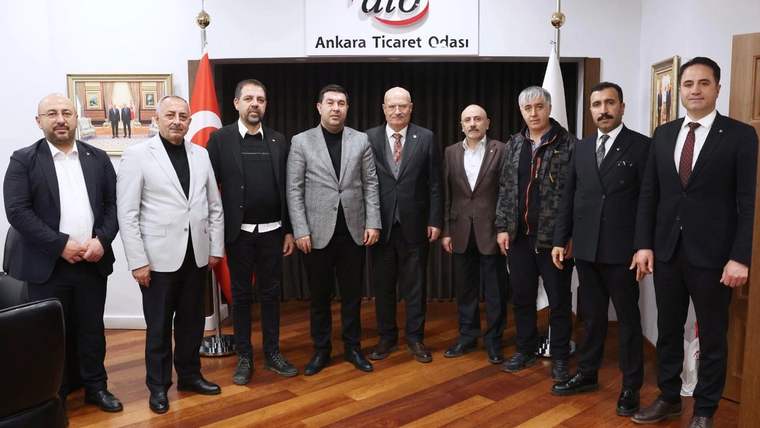 Ankara Ticaret Odası tabelasının önünde, Türk bayrakları arasında dokuz kişi yan yana duruyor.