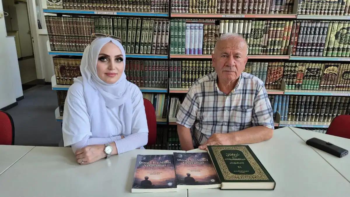 Bir kadın ve bir adam, masada kitapların önünde oturuyor. Arkada kitap rafları var.
