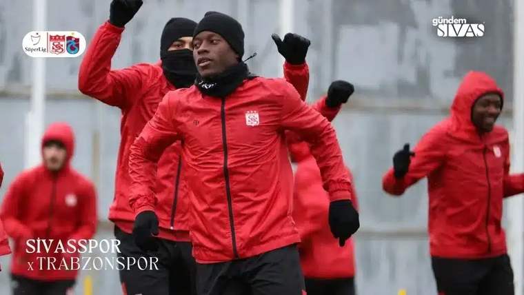Kırmızı antrenman kıyafetleri giymiş futbolcular, antrenman yapıyor.