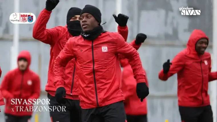 Kırmızı antrenman kıyafetleri giymiş futbolcular, antrenman yapıyor.