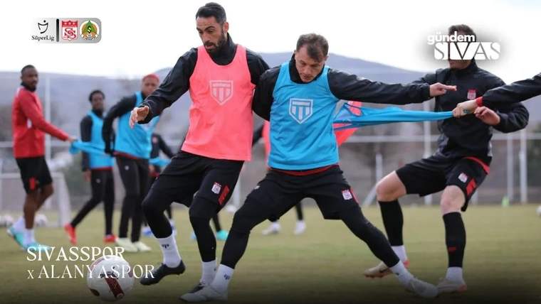 Antrenman sahasında pembe ve mavi yelekli futbolcular, top kapma çalışması sırasında mücadele ediyor.