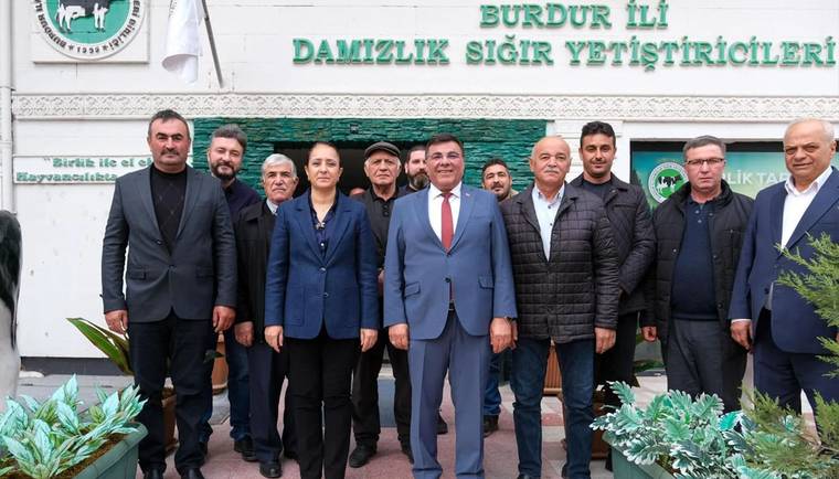 “Burdur İli Damızlık Sığır Yetiştiricileri” yazılı bina önünde poz veren bir grup yetişkin