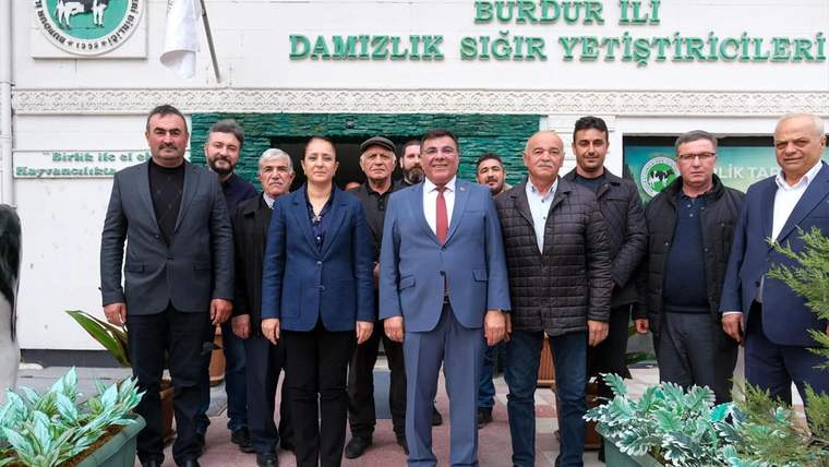 “Burdur İli Damızlık Sığır Yetiştiricileri” yazılı bina önünde poz veren bir grup yetişkin