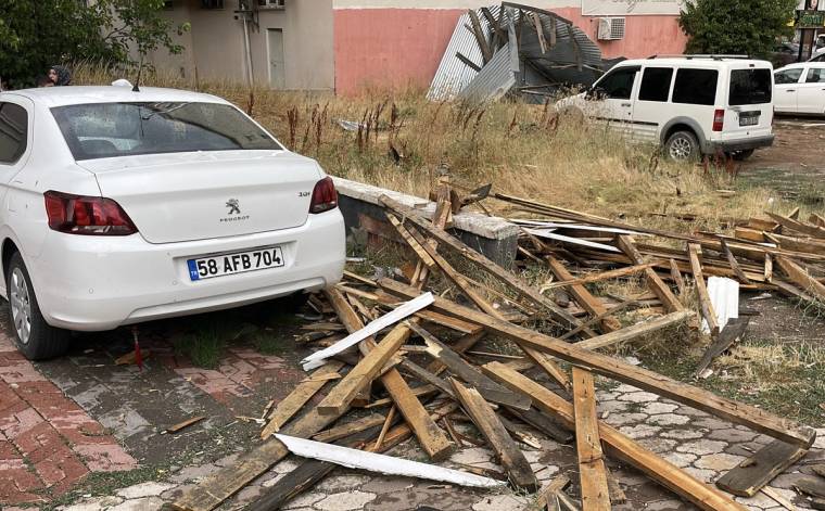 Park halindeki beyaz otomobillerin yanında, kaldırıma ve yola dağılmış kırık ahşap parçaları görülüyor.