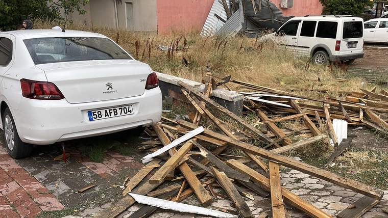 Park halindeki beyaz otomobillerin yanında, kaldırıma ve yola dağılmış kırık ahşap parçaları görülüyor.
