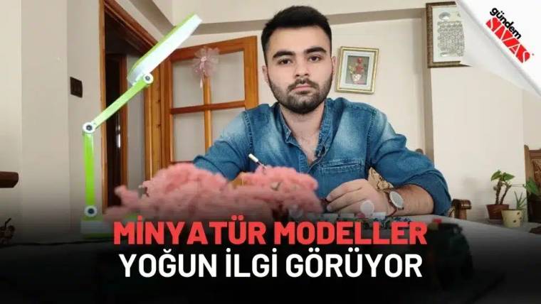 Bir masa üzerinde oturan bir kişi, minyatür modellerle çalışıyor.