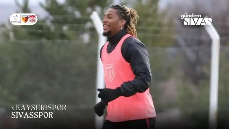 Antrenman sırasında pembe yelek giymiş bir futbolcu, gülümseyerek koşuyor.