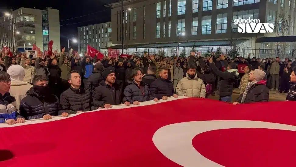 Büyük bir Türk bayrağı tutan kalabalık, gece yürüyüşü yapıyor.