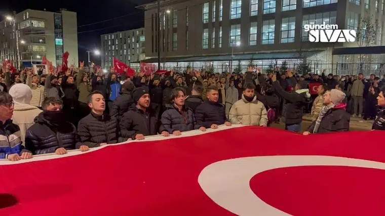 Büyük bir Türk bayrağı tutan kalabalık, gece yürüyüşü yapıyor.