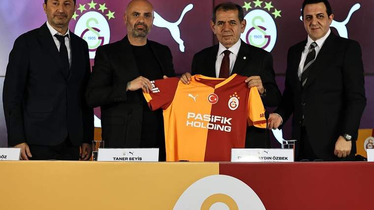 Dört erkek, üzerinde Galatasaray arması ve Puma logosu bulunan turuncu formayı birlikte tutuyor.
