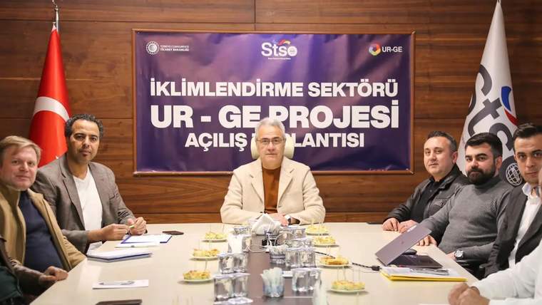 Toplantı masasında oturan kişiler, arkalarında “İklimlendirme Sektörü UR-GE Projesi Açılış Toplantısı” yazılı pankartla görülüyor.