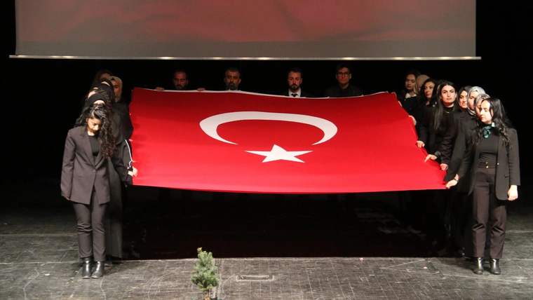 Türk bayrağını tutan genç öğretmenler, sahnede bir araya gelmiş.