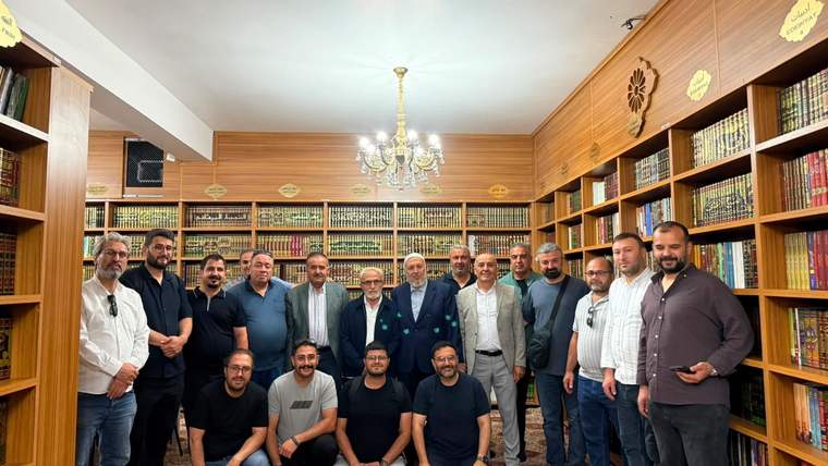 Kitaplıklarla çevrili süslü bir salonda, kalabalık bir erkek grubu ayakta ve önde oturarak poz veriyor.