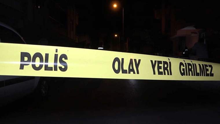 Gece karanlığındaki sokakta, üzerinde “POLİS OLAY YERİ GİRİLMEZ” yazan şerit uzanıyor.