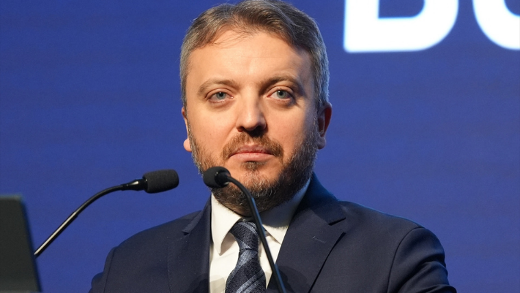 Kürsüde konuşan bir kişi, mikrofonun önünde duruyor.