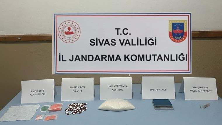 Sivas Valiliği İl Jandarma Komutanlığı tabelası önünde etiketli paketler, haplar, beyaz toz ve hassas terazi bulunuyor.