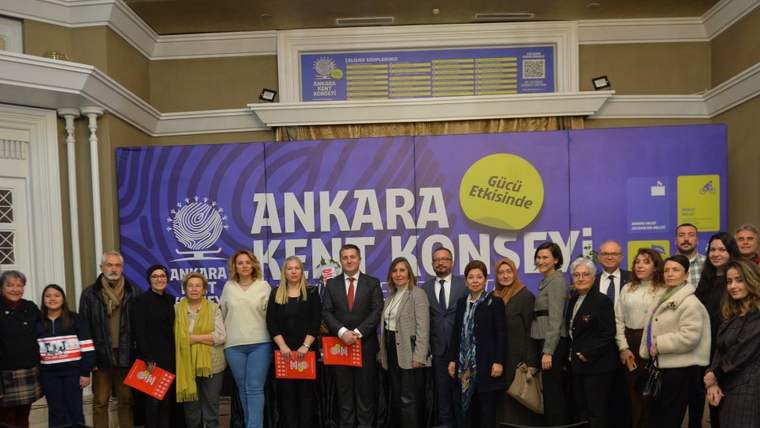 Üzerinde “Ankara Kent Konseyi” yazan mor pankart önünde, ellerinde kırmızı dosyalar bulunan bir grup poz veriyor.