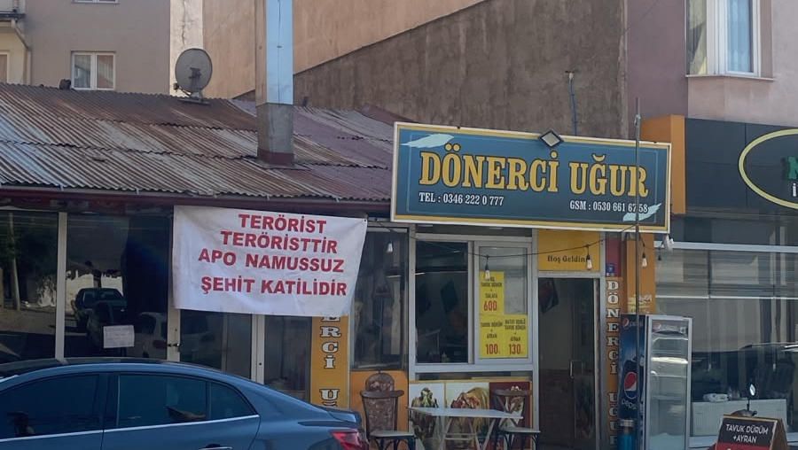 Dönerci Uğur dükkânının önünde, üzerinde protesto ifadeleri bulunan bir pankart asılı duruyor.