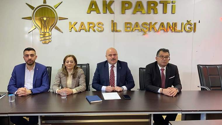 AK PARTİ KARS İL BAŞKANLIĞI yazılı duvar önünde masada oturan dört kişi