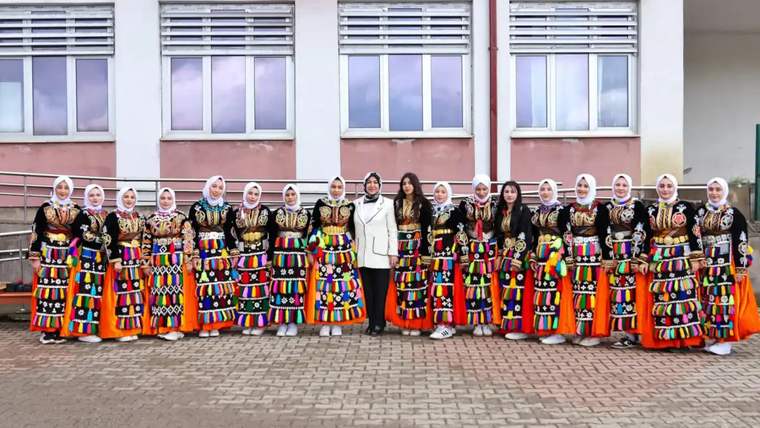 Geleneksel kıyafetler giymiş genç kızlar, bir grup halinde poz veriyor.