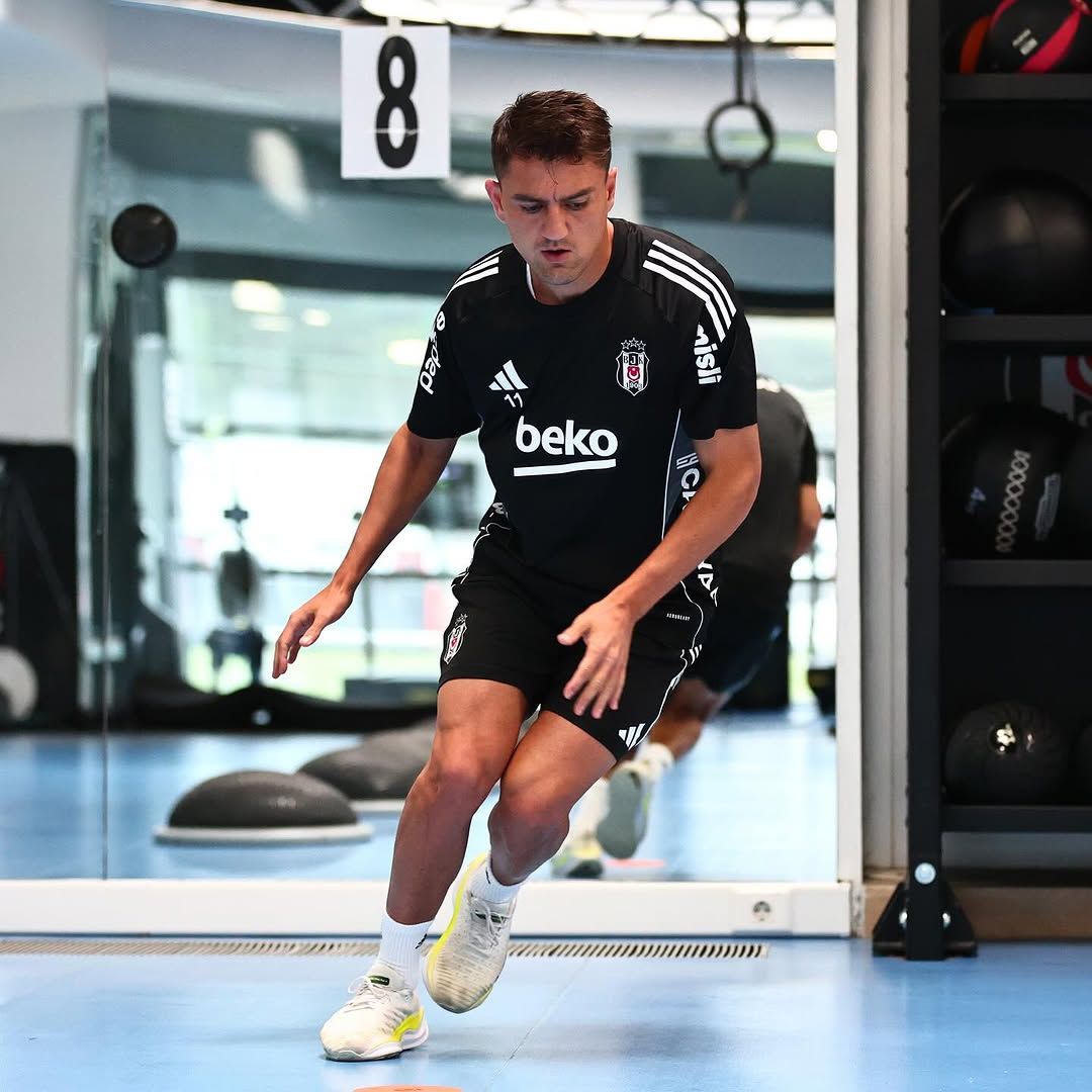 Siyah forma giymiş bir futbolcu, spor salonunda antrenman yapıyor.