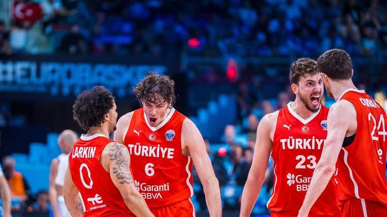 Kırmızı formalarında Türkiye yazan dört basketbolcu, sahada birbirlerine sarılarak ve sevinçle kutlama yapıyor.