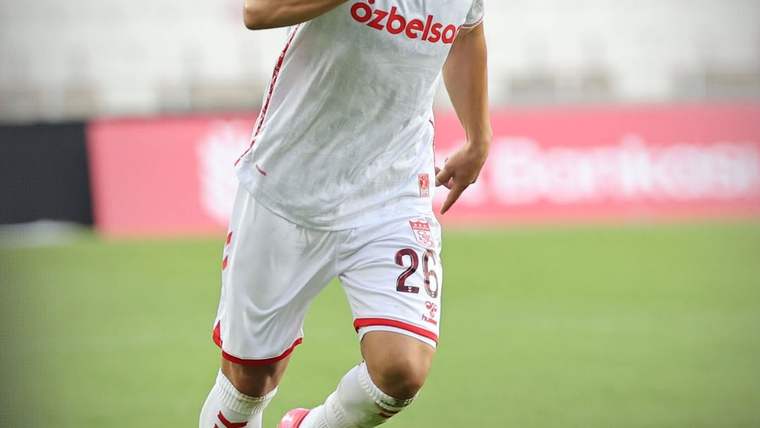 Beyaz formalı, üzerinde 28 numarası bulunan futbolcu, yeşil sahada koşarken görülüyor.