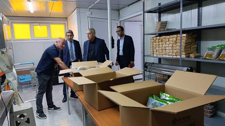 Dört kişinin bulunduğu işletmede açık karton kutular masalarda, raflarda paketlenmiş ürünler görülüyor.