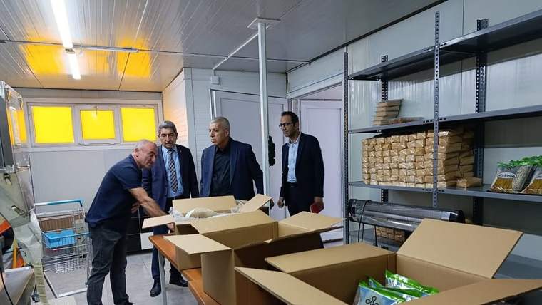 Dört kişinin bulunduğu işletmede açık karton kutular masalarda, raflarda paketlenmiş ürünler görülüyor.