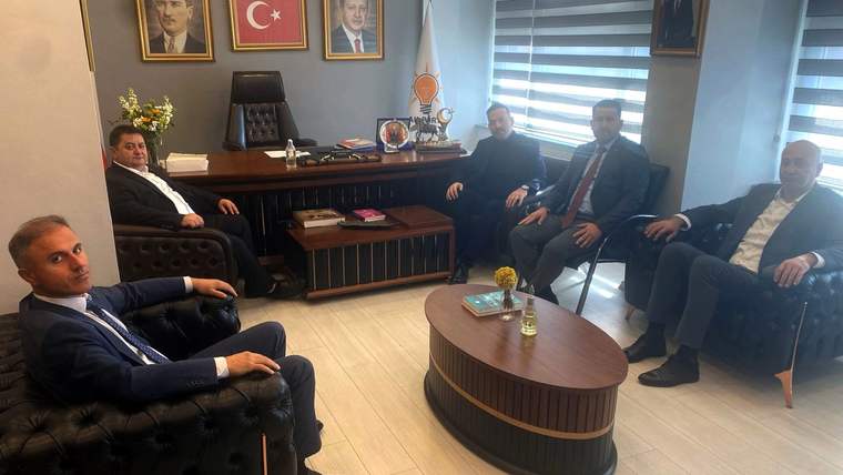Makam odasında masa çevresinde oturan beş erkek, duvarda Türk bayrağı ve çeşitli portreler görülüyor.