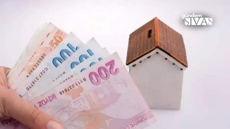 Bir el, küçük bir ev maketi önünde 200 ve 100 liralık Türk lirası banknotlarını tutuyor.