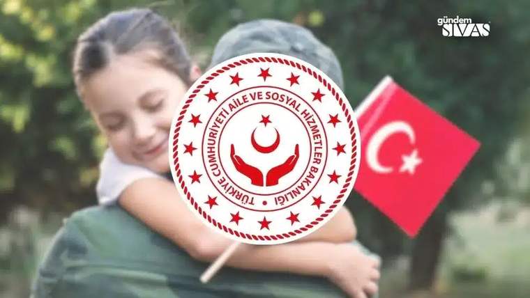 Bir çocuk, elinde Türk bayrağı tutan kamuflajlı bir yetişkine sarılıyor; önde kurum amblemli çubuk var.