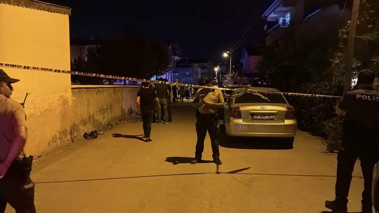 Gece vakti polis şeridiyle kapatılmış sokakta polisler ve park halindeki bir otomobil görülüyor.