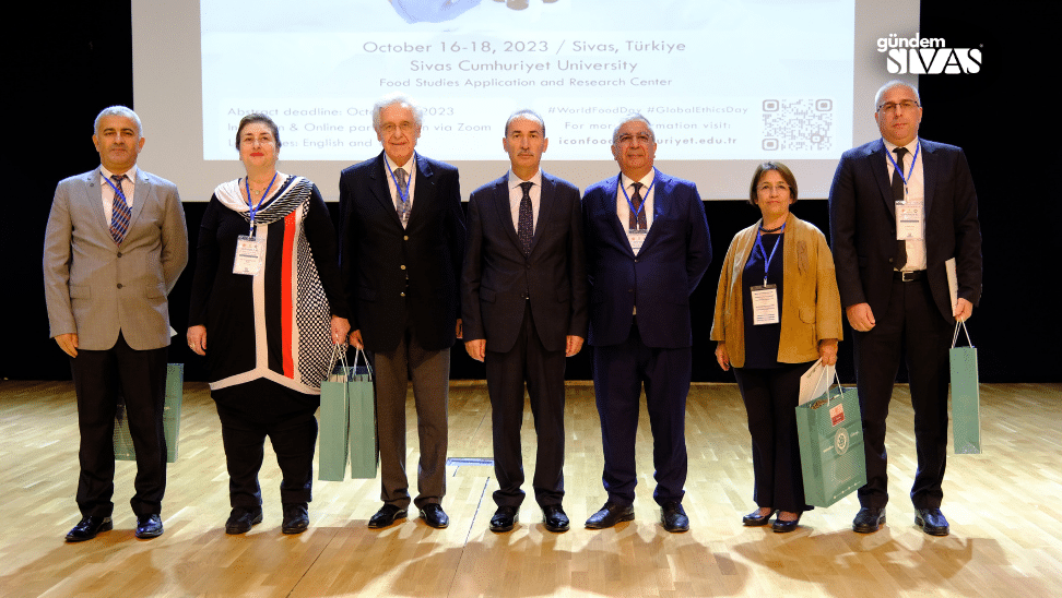 Sivas Cumhuriyet Üniversitesi'nde Gıda Araştırmaları Kongresi'ne katılan sekiz kişi, sahnede bir arada duruyor.