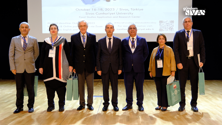 Sivas Cumhuriyet Üniversitesi'nde Gıda Araştırmaları Kongresi'ne katılan sekiz kişi, sahnede bir arada duruyor.
