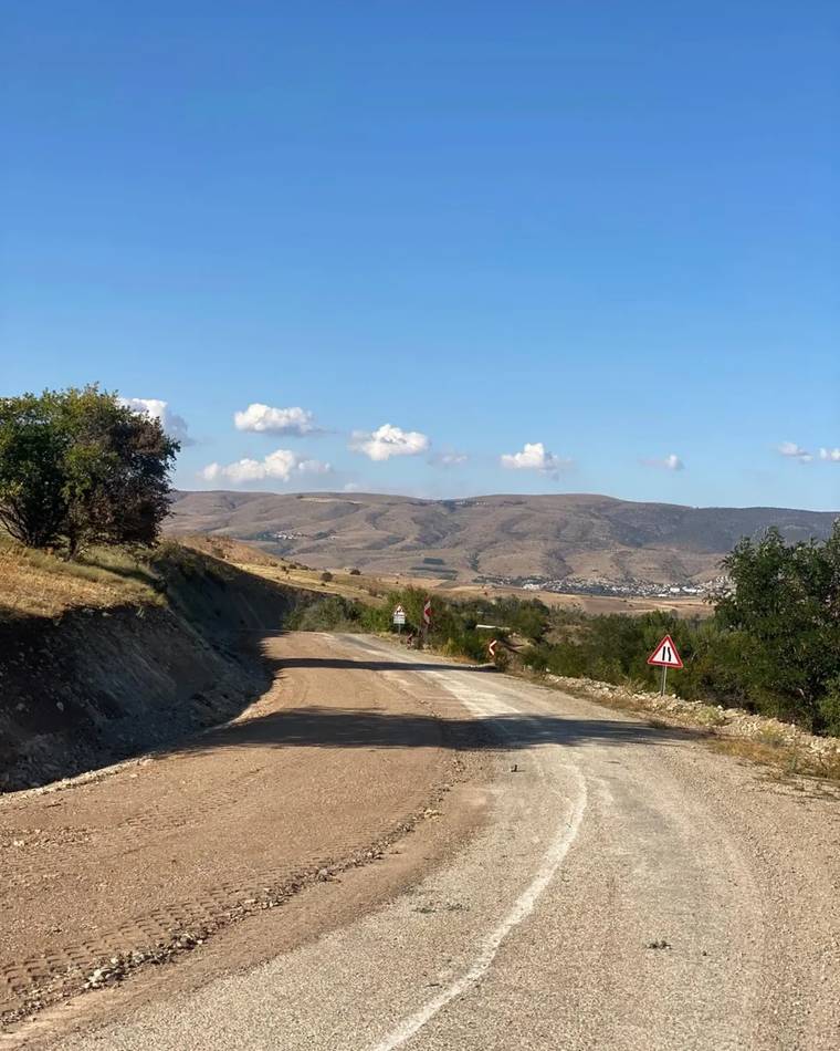 Sivas Gölova'da toprak yol, çevresinde ağaçlar ve dağ manzarasıyla birlikte görünmektedir.