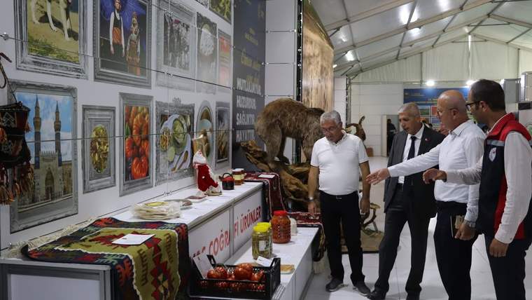 Fuar alanında, tarım ve hayvancılık ürünlerinin sergilendiği stantta birkaç kişi inceleme yapıyor.