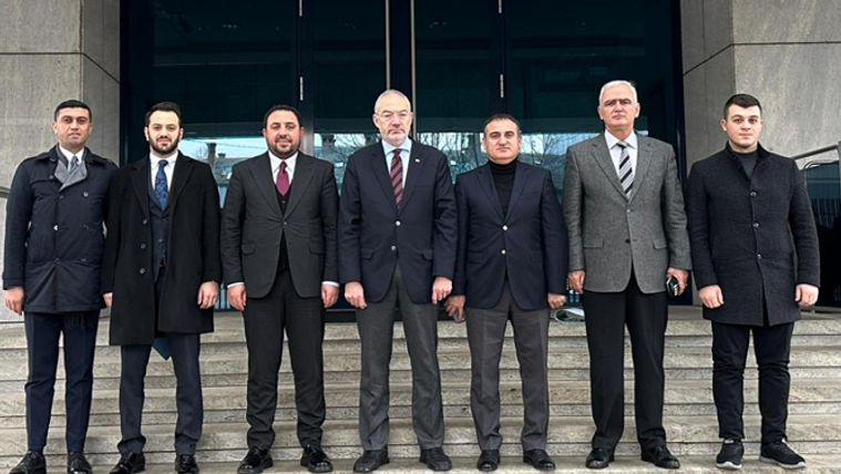 Bina girişinin merdivenlerinde takım elbiseli ve paltolu yedi erkek yan yana duruyor.