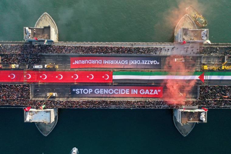 Havadan görülen, kalabalıklarla dolu köprüde Türk bayrakları ve “STOP GENOCIDE IN GAZA” yazılı pankartlar bulunuyor.