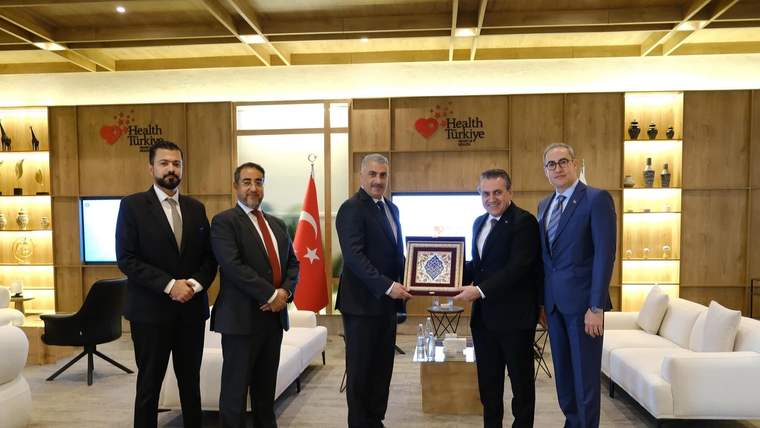 Health Türkiye yazılı panoların önünde beş kişi, ortada çerçeveli bir plaketi tutuyor; arkada Türk bayrağı var.