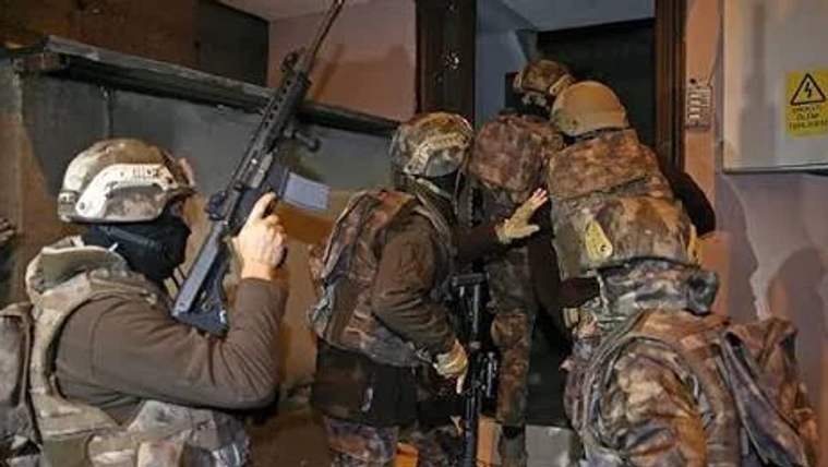 Askeri kıyafet giymiş birkaç kişi, kapıdan içeri girmeye çalışıyor.
