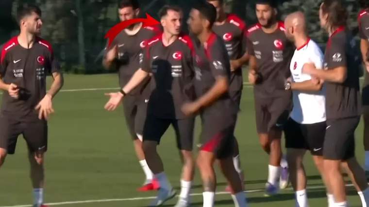 Yeşil sahada ay-yıldızlı antrenman kıyafetleri giyen futbolcular birlikte yürürken kırmızı ok görülüyor.