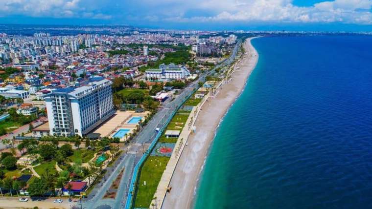 Kıyı boyunca uzanan kumsalın yanında oteller, yollar ve yoğun yerleşim alanları; açık deniz manzarası