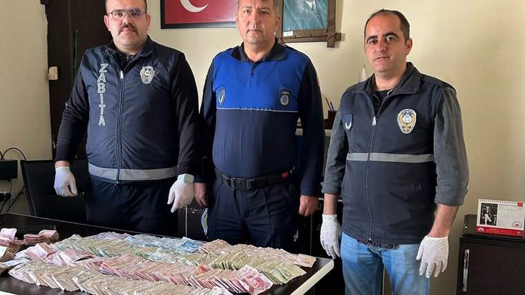 Üç görevli, üzerinde çok sayıda banknot bulunan masanın arkasında, bir odada yan yana duruyor.