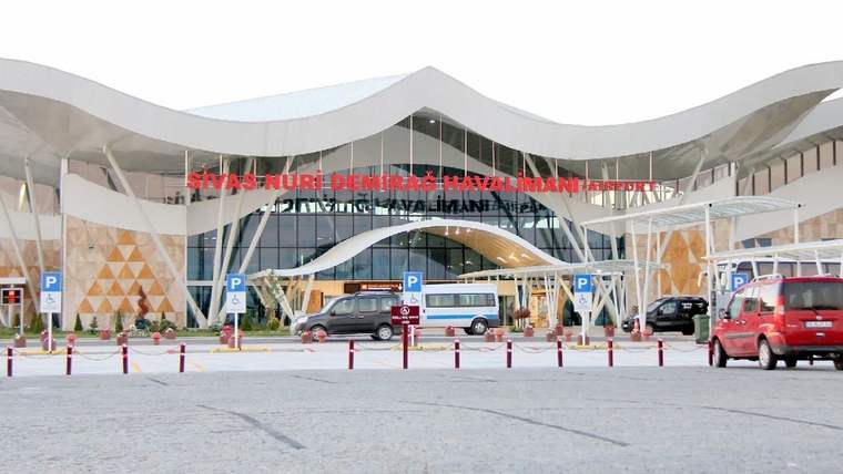 Sivas Nuri Demirağ Havalimanı'nın dış cephesi, önünde park etmiş araçlar ve yolcu giriş kapısı görünmekte.